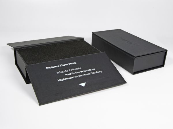 Die Flap Box mit bedruckter Innenseite auf einer Klappe - Mit Hoch- und Tiefenprägung des Logos auf den Oberseiten - Mit einem Inlay aus weichem Schaumstoff.